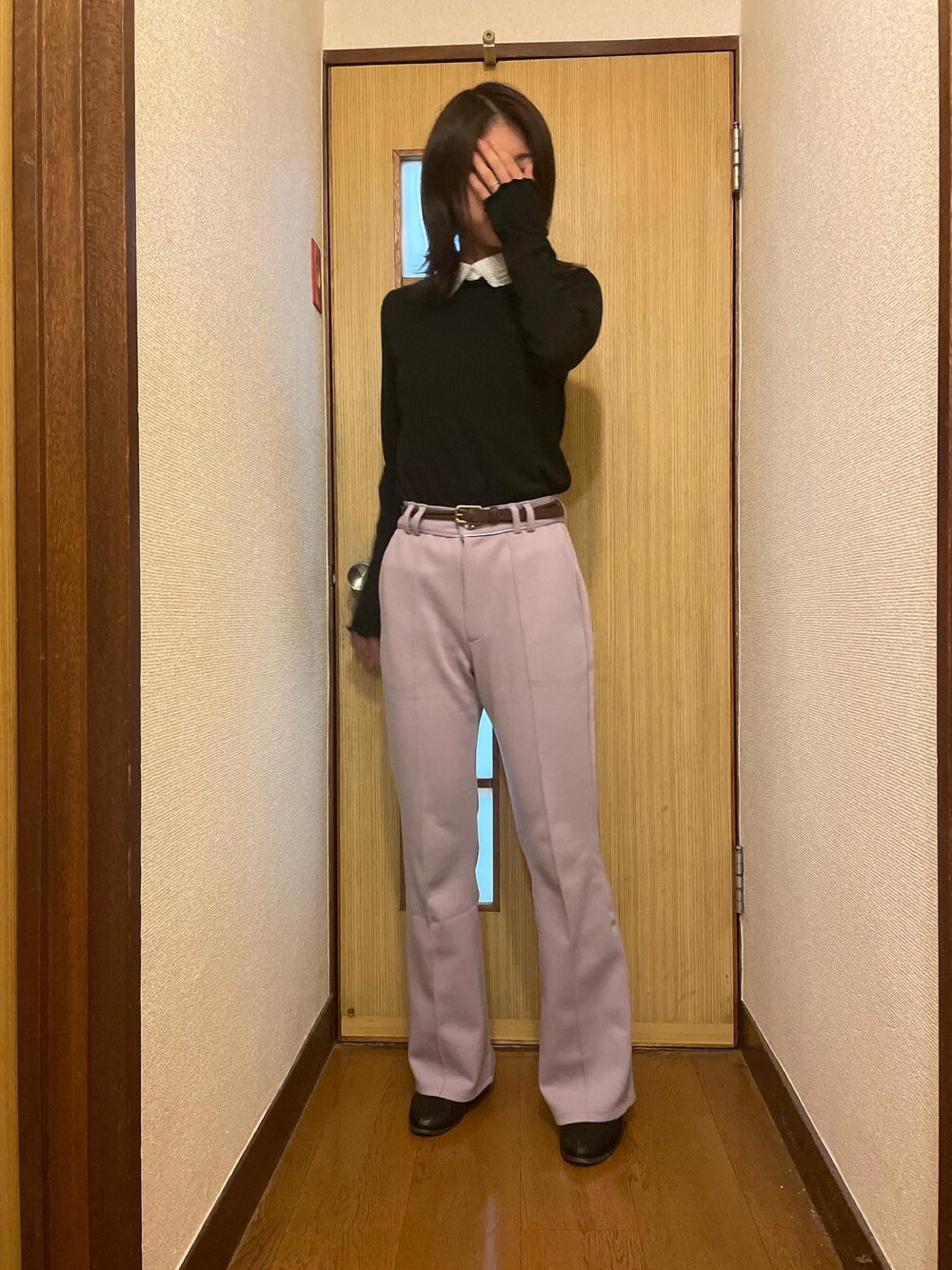 ピンク系のパンツ、ブラック系のトップス、ベージュ系のステンカラーコートを着用したレディースの冬コーディネートの1枚目の写真