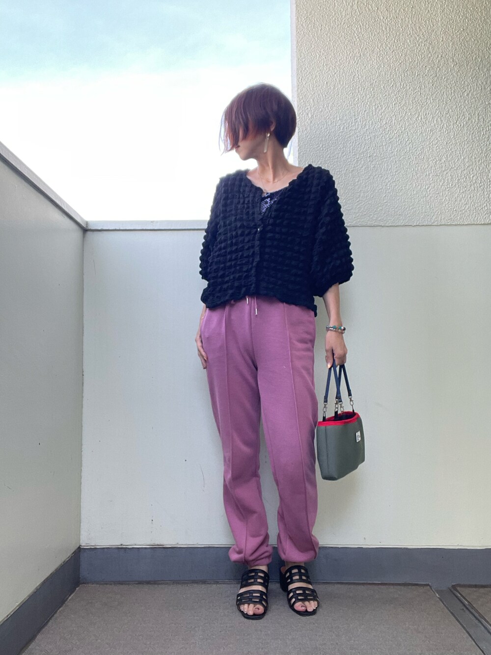 ピンク系のスウェットパンツ、グリーン系のバッグ、ブラック系のサンダルを着用したレディースの秋コーディネートの1枚目の写真