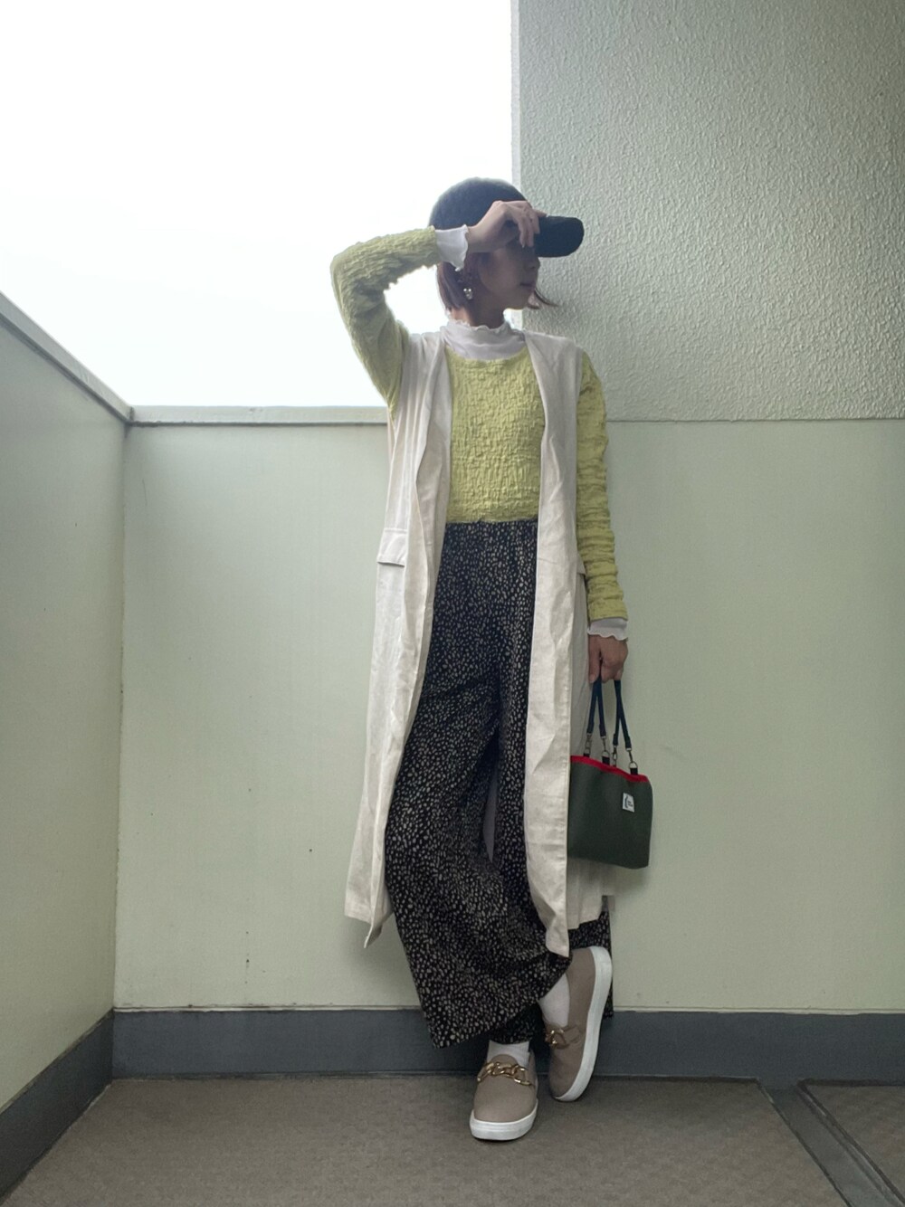 ブラック系のその他パンツ、その他のスニーカー、ベージュ系のベストを着用したレディースの春コーディネートの1枚目の写真