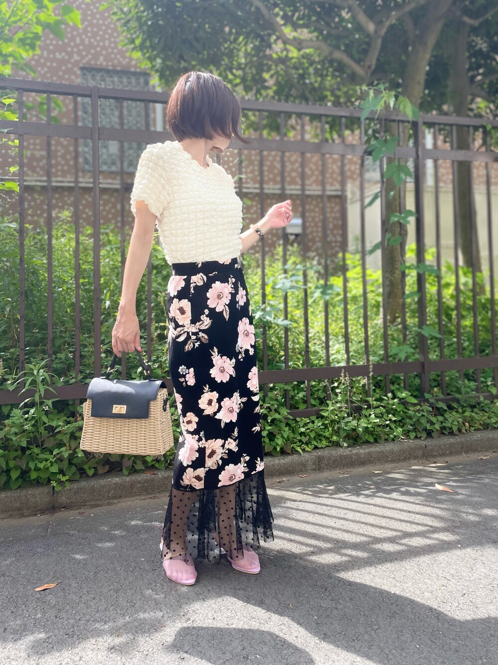 ベージュ系のバッグ、ブラック系のスカート、ホワイト系のTシャツ/カットソーを着用したレディースの夏コーディネートの1枚目の写真