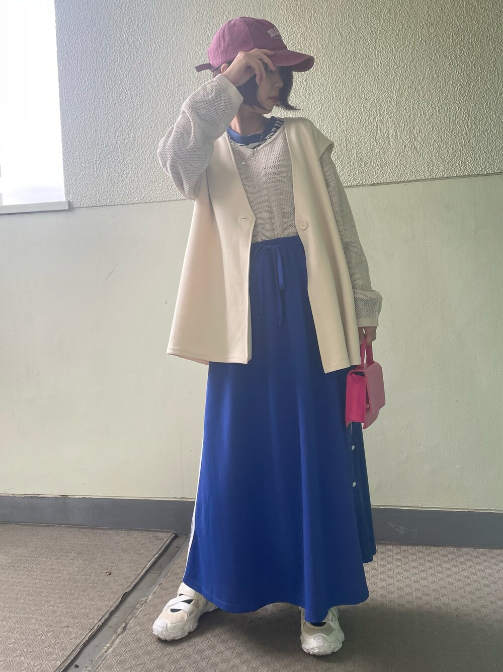 ブルー系のスカート、ホワイト系のシューズ、ピンク系のバッグを着用したレディースの春コーディネートの1枚目の写真