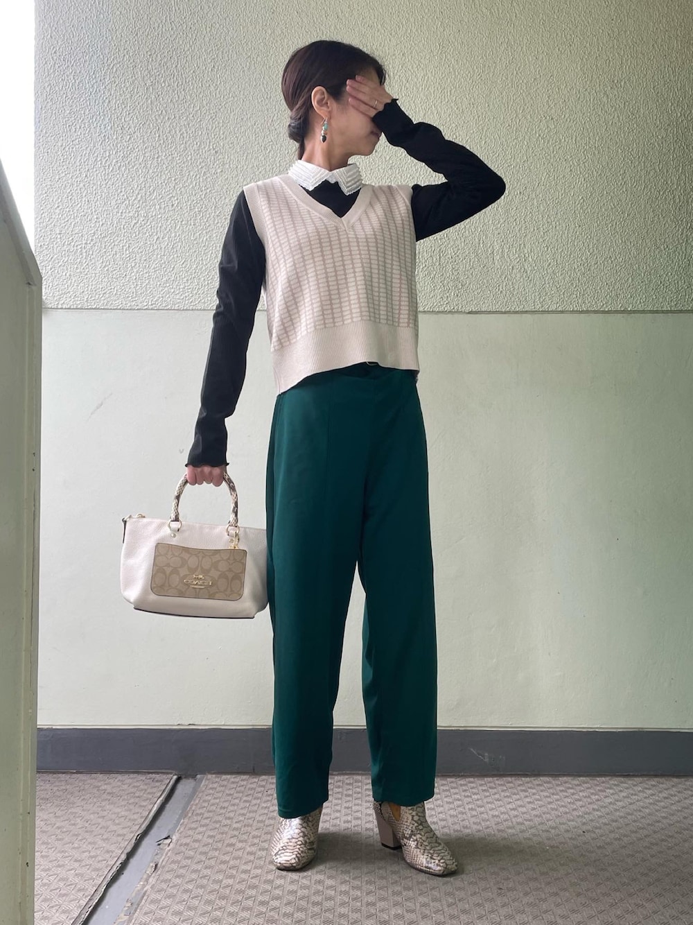 グリーン系のパンツ、その他のローファー、ホワイト系のバッグを着用したレディースの冬コーディネートの1枚目の写真