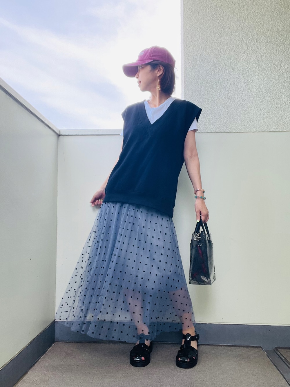 ブルー系のスカート、ブラック系のバッグ、ブラック系のサンダルを着用したレディースの夏コーディネートの1枚目の写真