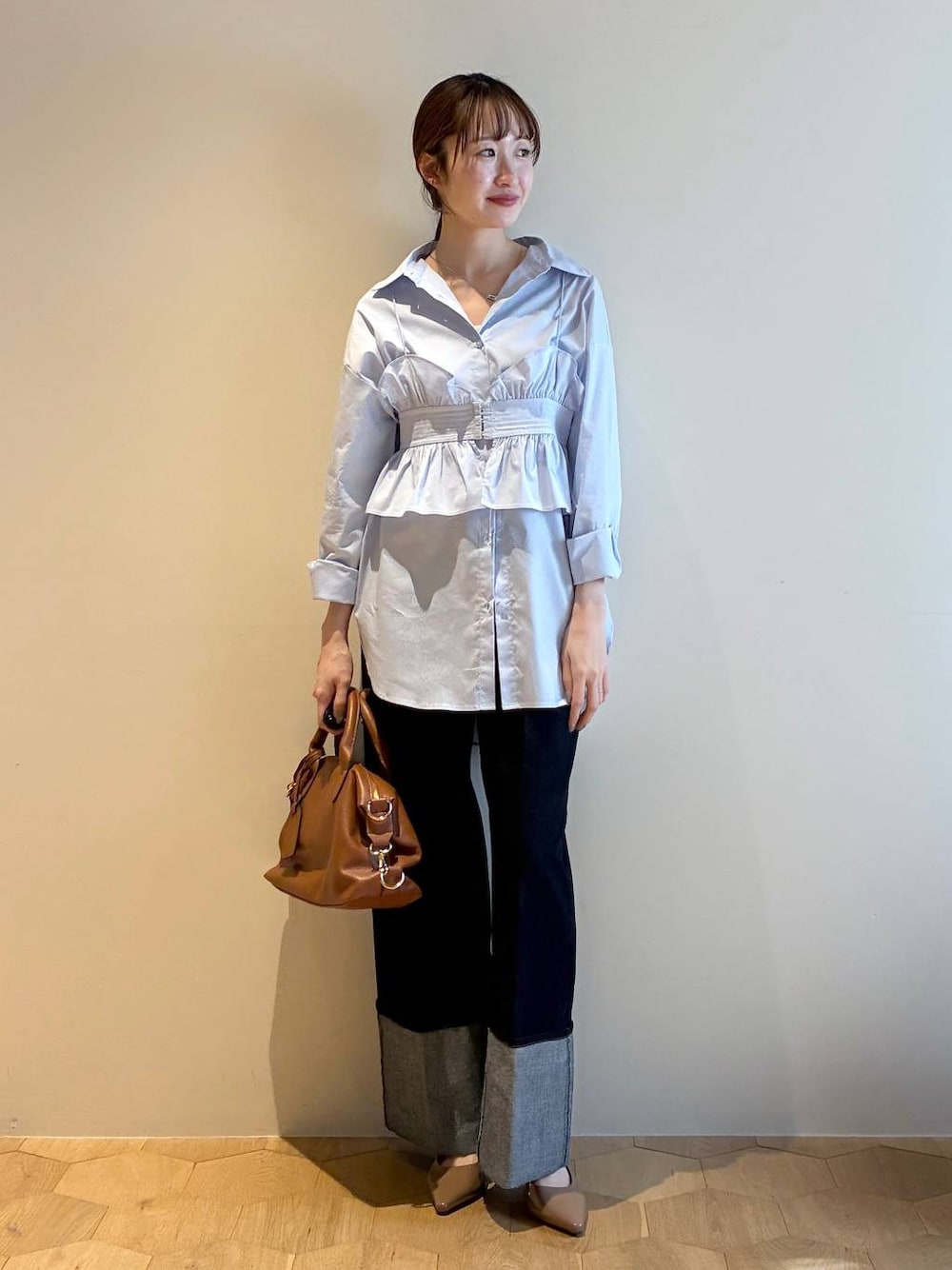 ブラウン系のボストンバッグ、ブラウン系のサンダル、ブルー系のシャツ/ブラウスを着用したレディースの冬コーディネートの1枚目の写真