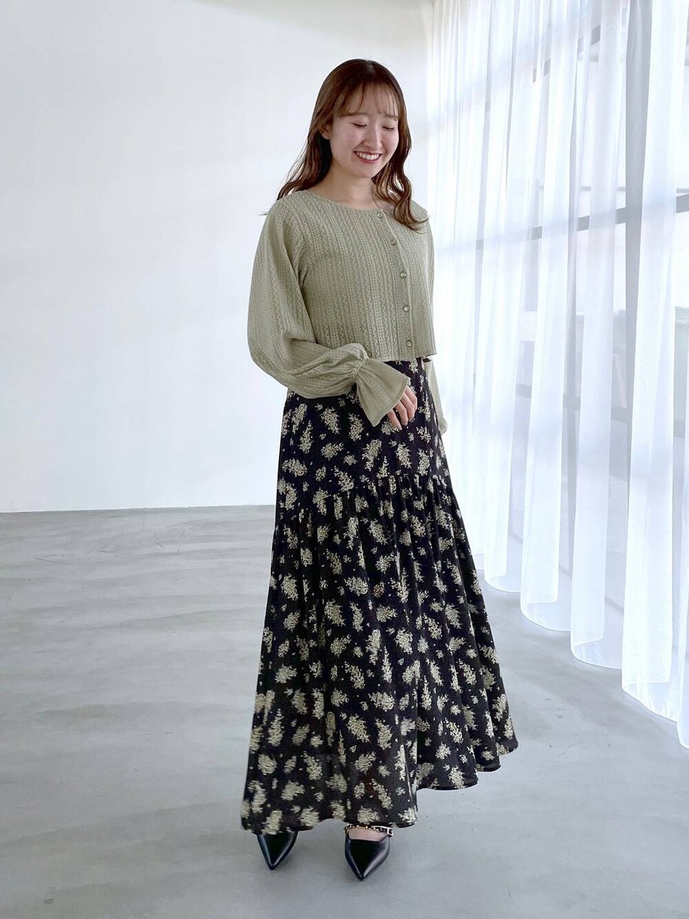 ブラック系のスカート、グリーン系のTシャツ/カットソー、ブラック系のパンプスを着用したレディースの冬コーディネートの1枚目の写真