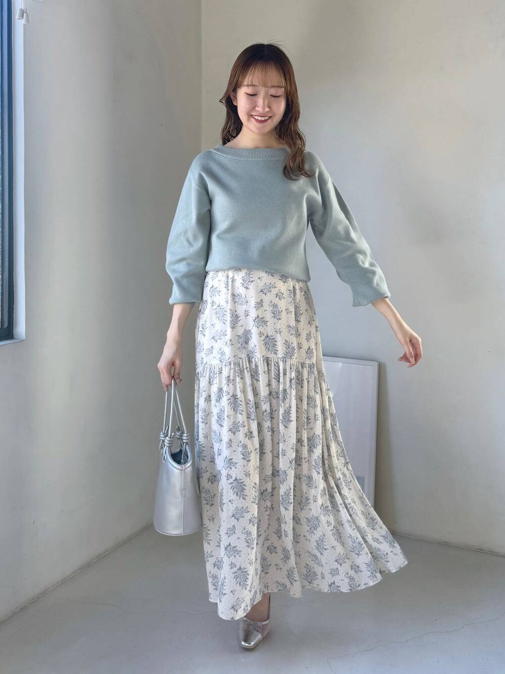 シルバー系のバレエシューズ、ブルー系のスカート、グリーン系のニット/セーターを着用したレディースの冬コーディネートの1枚目の写真