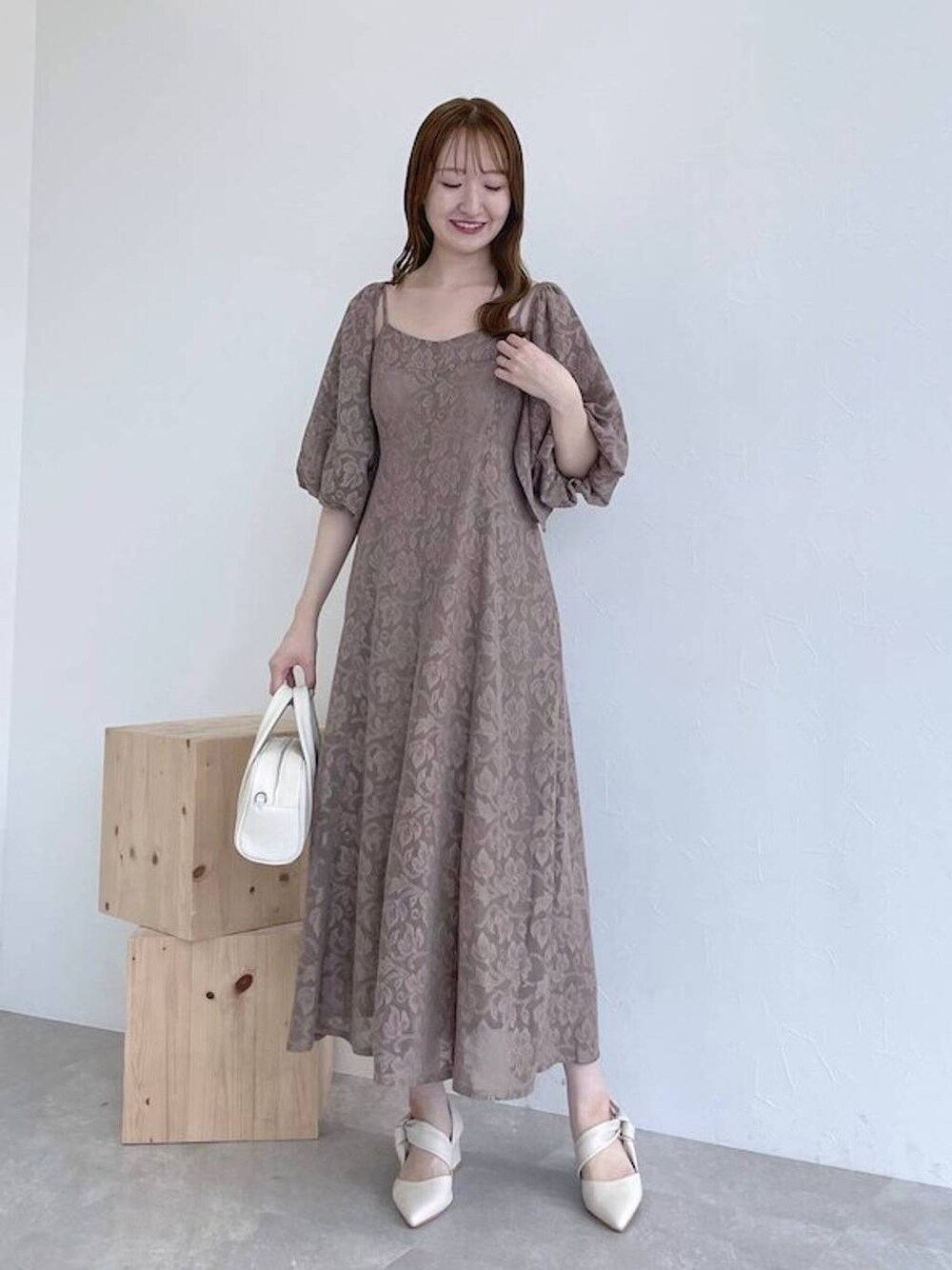 ホワイト系のボストンバッグ、ブラウン系のワンピース、ホワイト系のパンプスを着用したレディースの秋コーディネートの1枚目の写真