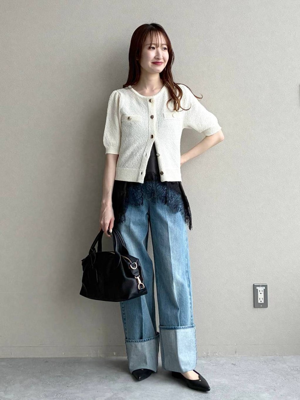 ブラック系のボストンバッグ、ホワイト系のカーディガン/ボレロ、ブラック系のパンプスを着用したレディースの春コーディネートの1枚目の写真