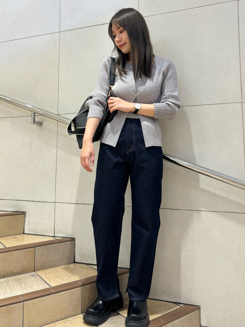 グレー系のニット/セーター、ブルー系のデニムパンツ、ブラック系のブーツを着用したレディースの冬コーディネートの1枚目の写真