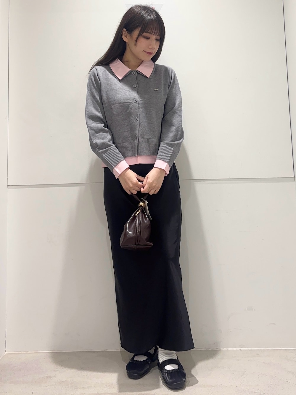 グレー系のカーディガン/ボレロ、ブラック系のスカート、ブラウン系のハンドバッグを着用したレディースの春コーディネートの1枚目の写真