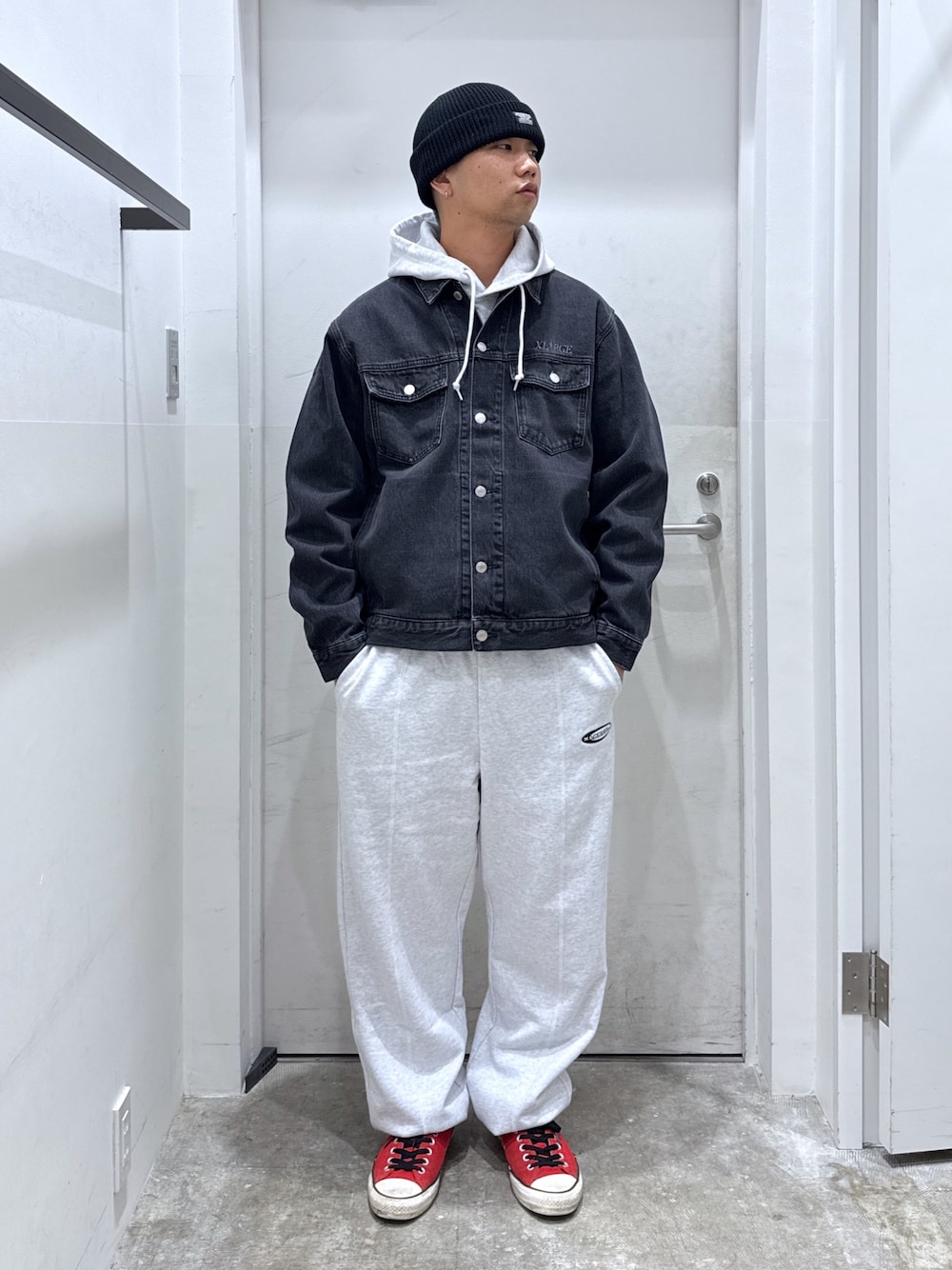 ブラック系のデニムジャケット、グレー系のパーカー、グレー系のスウェットパンツを着用したメンズの秋コーディネートの1枚目の写真