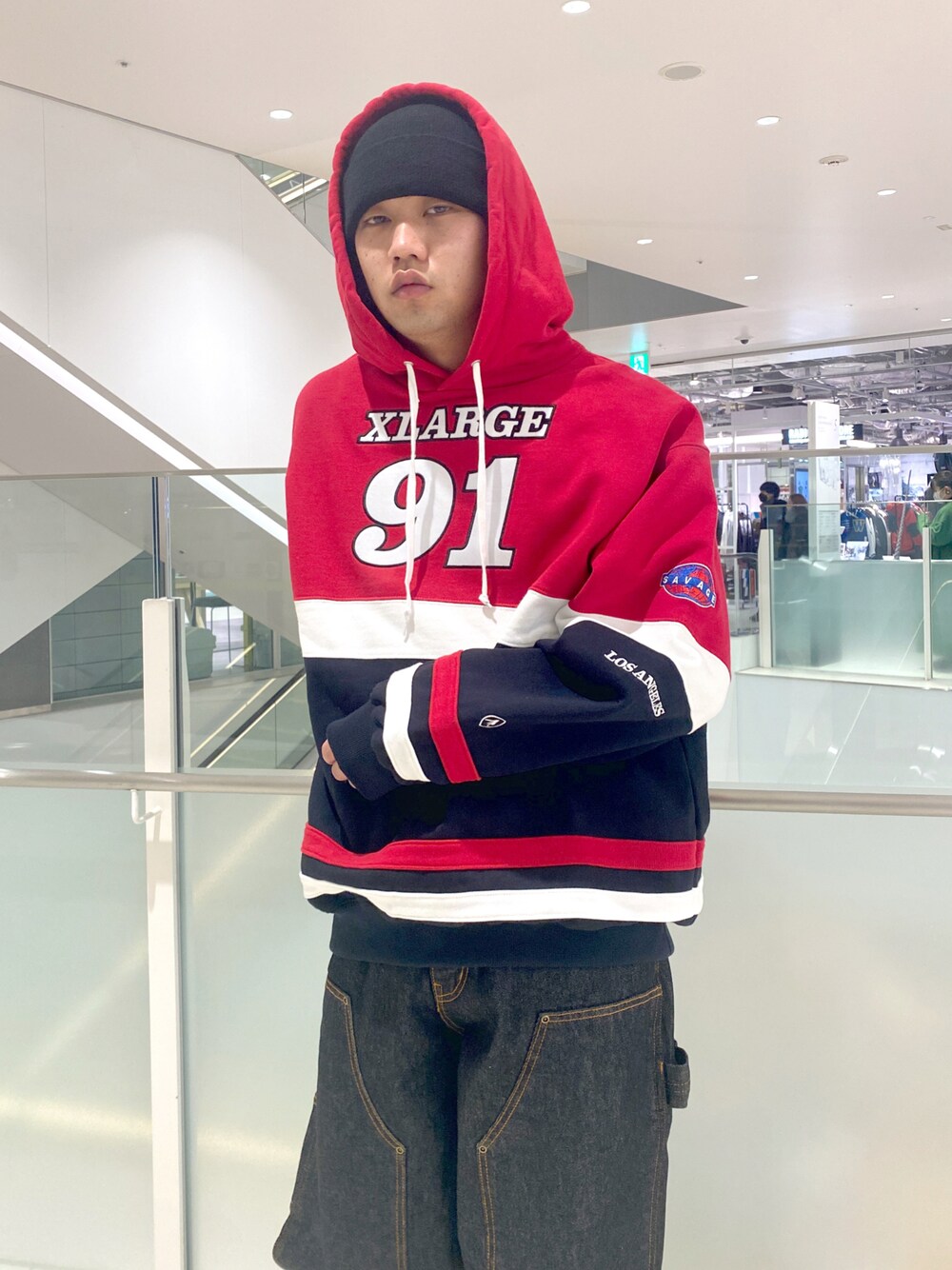 レッド系のパーカー、ブラック系のデニムパンツ、ブラック系のニットキャップ/ビーニーを着用したメンズの冬コーディネートの1枚目の写真