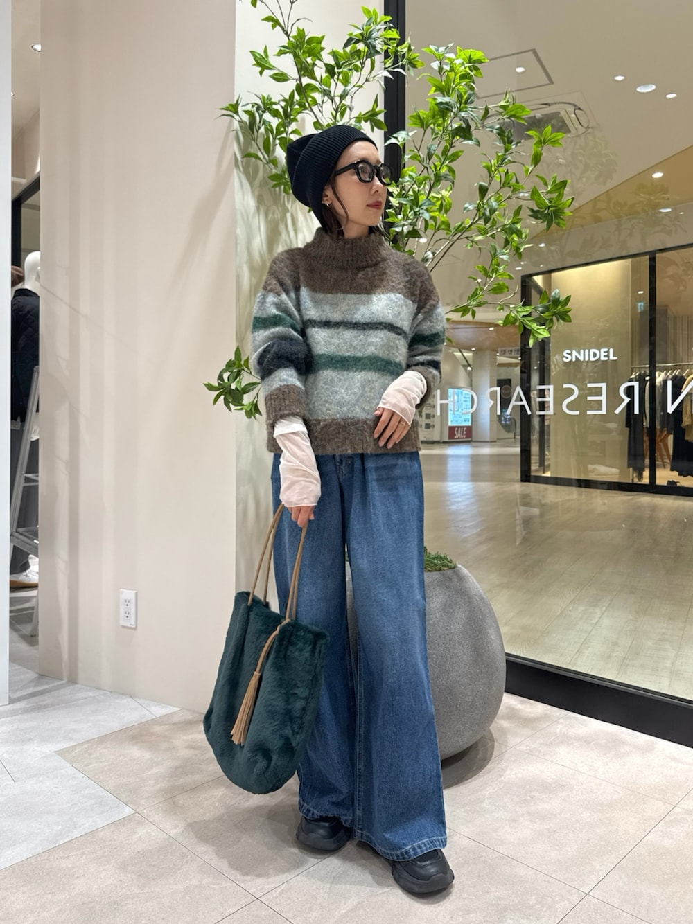 ブラウン系のニット/セーター、ホワイト系のTシャツ/カットソー、グリーン系のトートバッグを着用したレディースの秋コーディネートの1枚目の写真