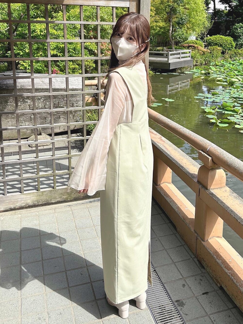 グリーン系のジャンパースカート、ベージュ系のシャツ/ブラウス、ベージュ系のブーツを着用したレディースの春コーディネートの1枚目の写真