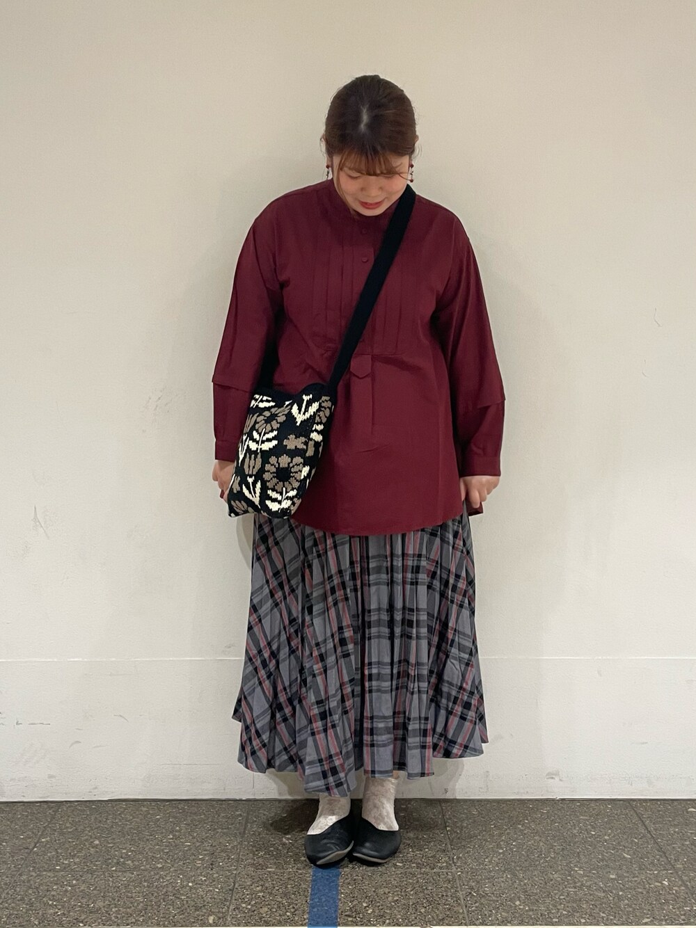 レッド系のチュニック、グレー系のスカート、ブラック系のハンドバッグを着用したレディースの秋コーディネートの1枚目の写真