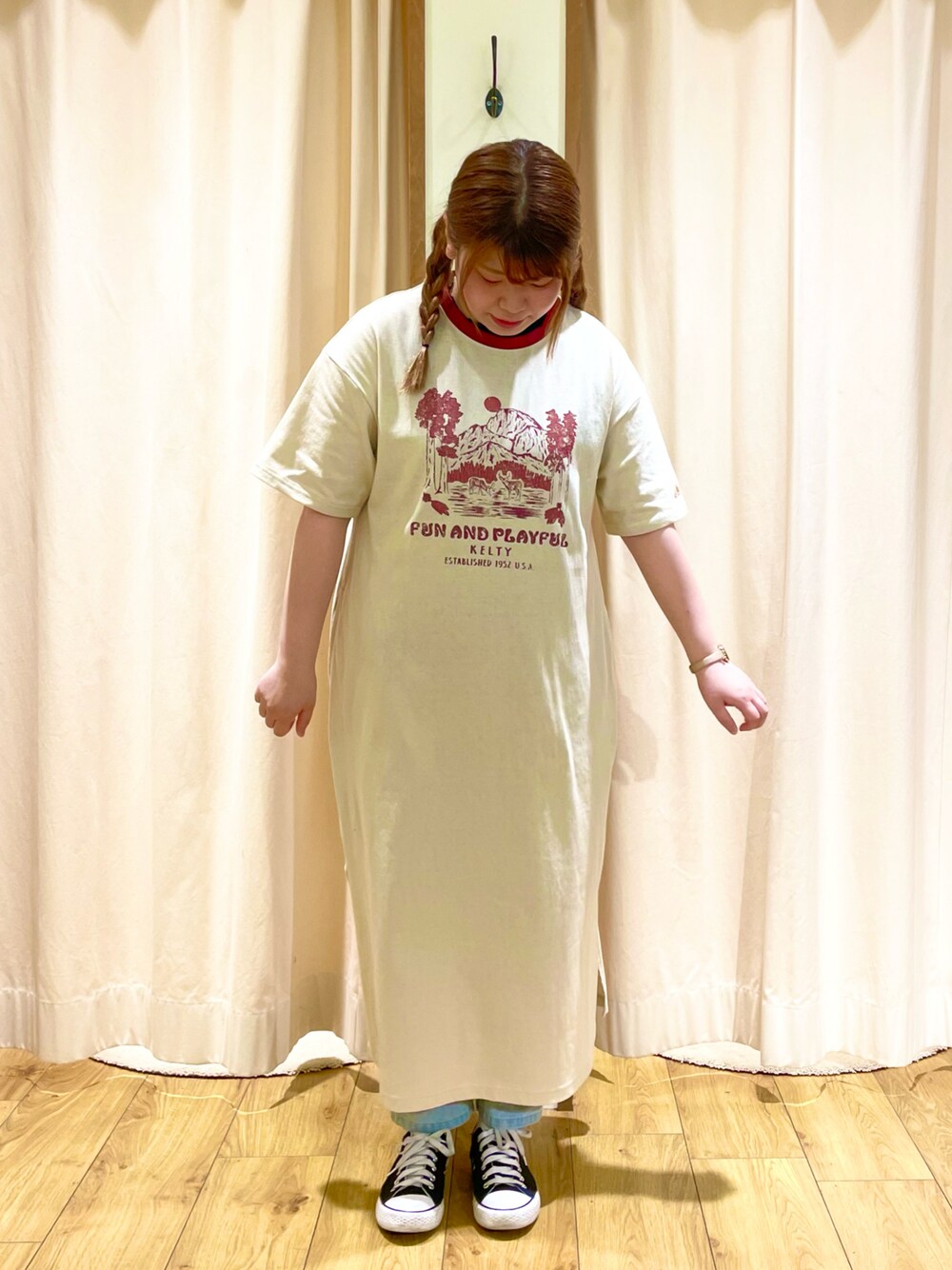 ベージュ系のワンピース、ブルー系のデニムパンツを着用したレディースの春コーディネートの1枚目の写真