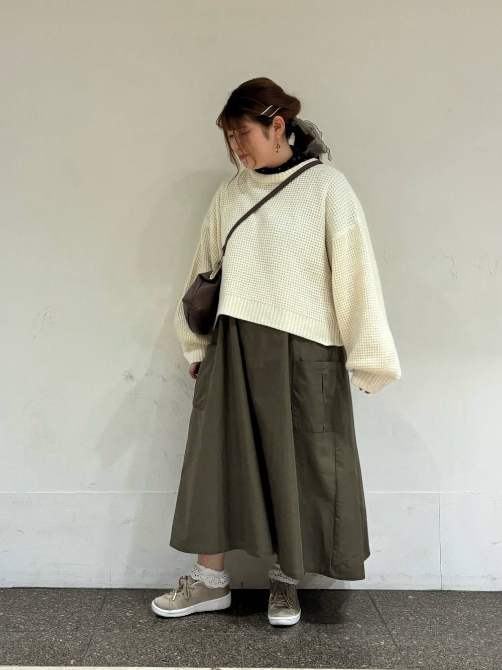 グリーン系のワンピース、ブラウン系のハンドバッグを着用したレディースの冬コーディネートの1枚目の写真