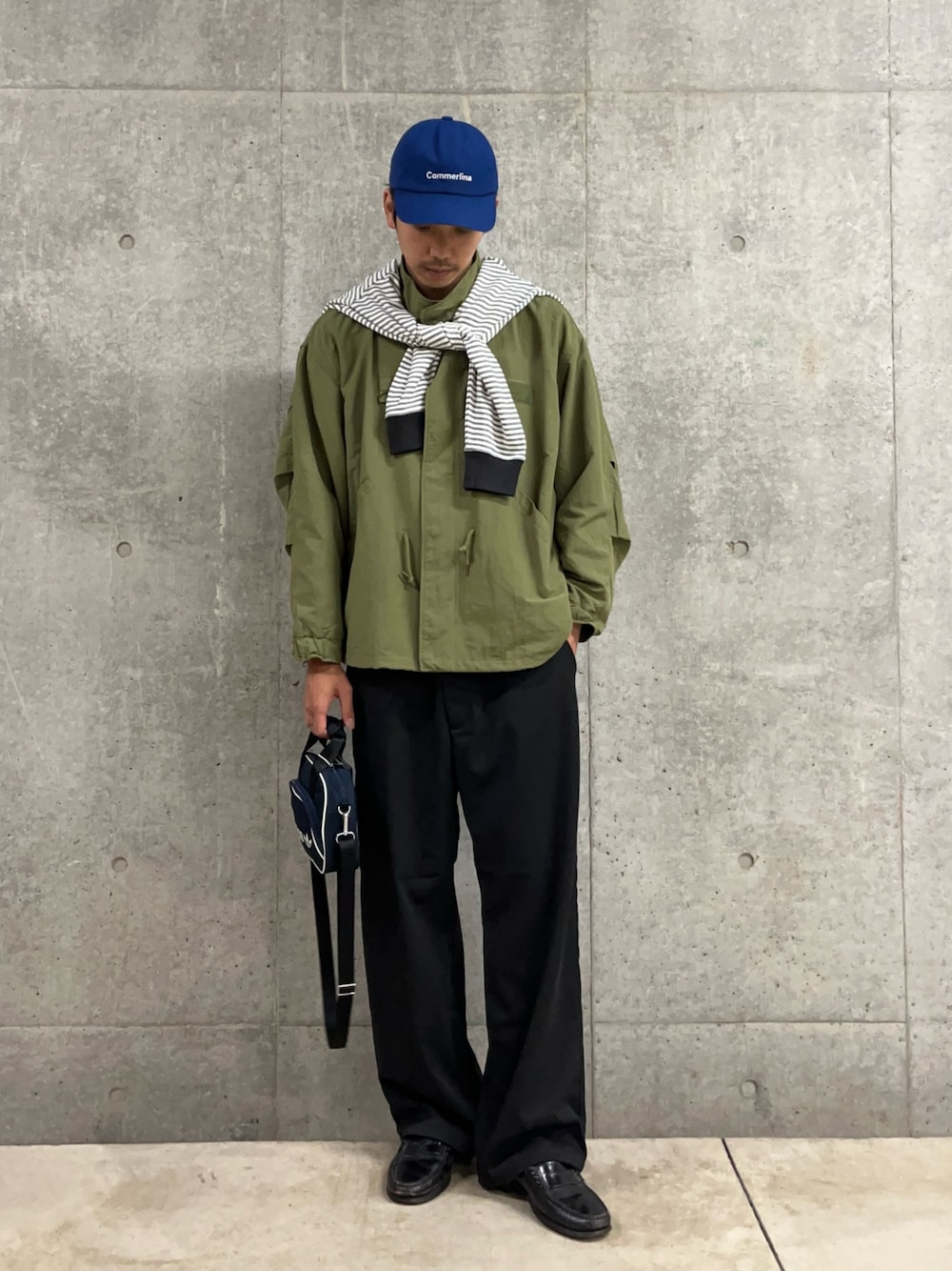 ブルー系のショルダーバッグ、ホワイト系のTシャツ/カットソー、グリーン系のブルゾンを着用したメンズの秋コーディネートの1枚目の写真