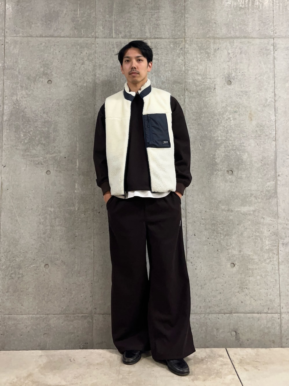 ブラウン系のスウェット、ホワイト系のダウンベスト、ブラウン系のその他パンツを着用したメンズの冬コーディネートの1枚目の写真