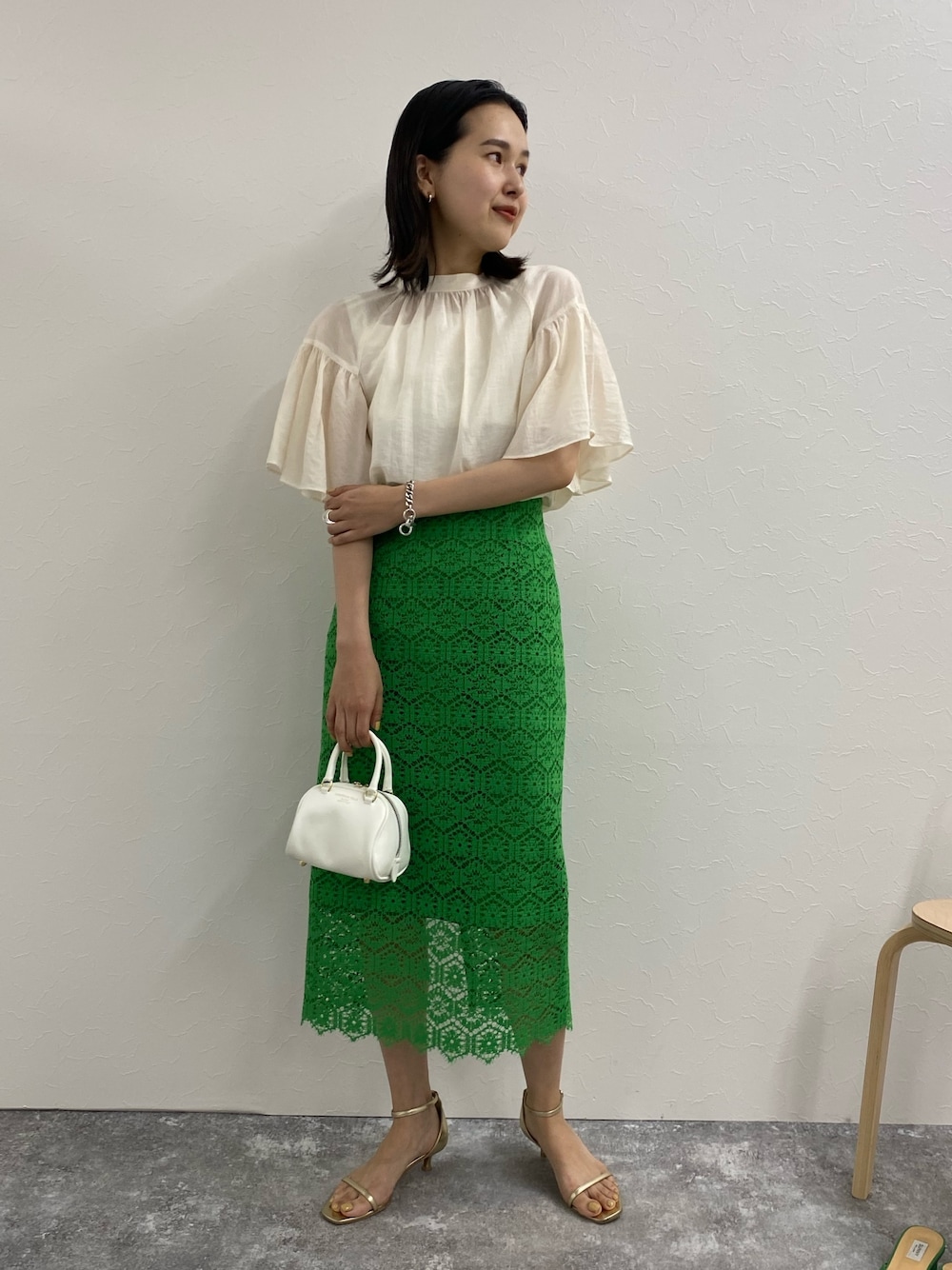 グリーン系のスカート、ホワイト系のシャツ/ブラウス、ゴールド系のサンダルを着用したレディースの春コーディネートの1枚目の写真