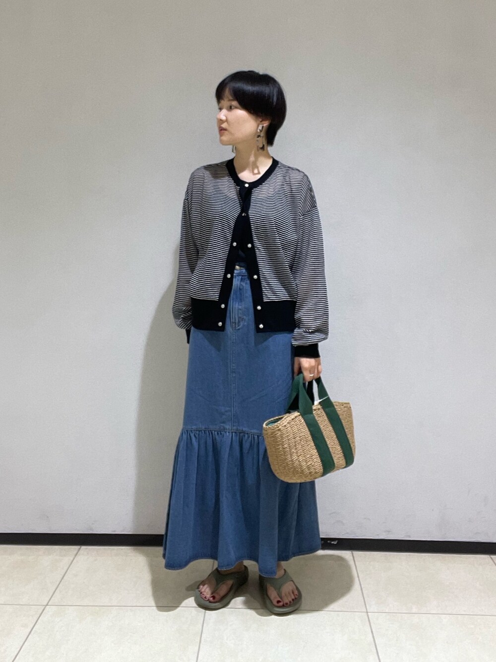 ブラック系のカーディガン/ボレロ、グリーン系のかごバッグ、ブルー系のデニムスカートを着用したレディースの夏コーディネートの1枚目の写真