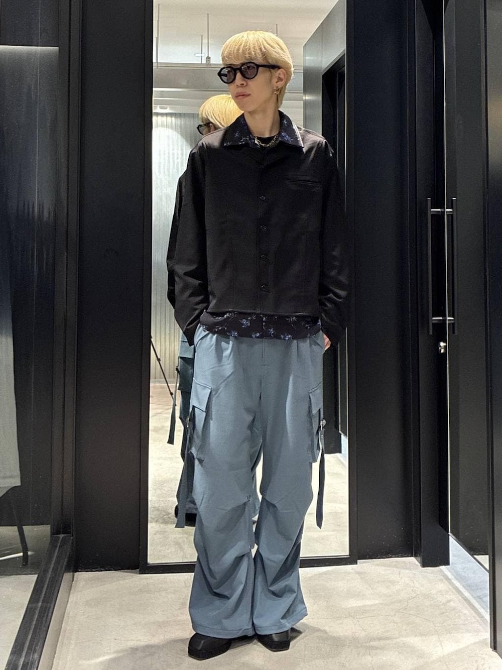 ブルー系のカーゴパンツ、ブラック系のサンダル、ブラック系のシャツ/ブラウスを着用したメンズの春コーディネートの1枚目の写真