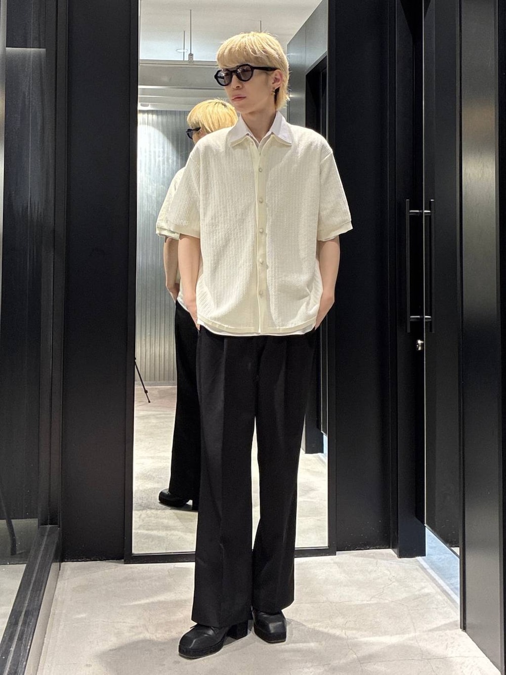 ブラック系のスラックス、ブラック系のサンダル、ホワイト系のニット/セーターを着用したメンズの春コーディネートの1枚目の写真