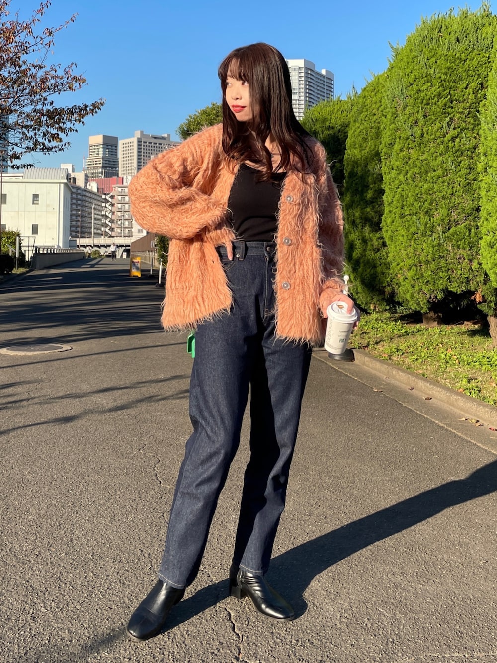 オレンジ系のカーディガン/ボレロ、ブルー系のデニムパンツ、ブラック系のショルダーバッグを着用したレディースの秋コーディネートの1枚目の写真