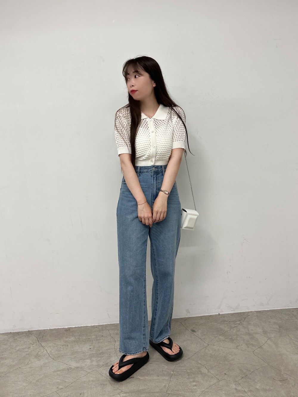 ホワイト系のカーディガン/ボレロ、ブルー系のデニムパンツ、ブラック系のサンダルを着用したレディースの春コーディネートの1枚目の写真