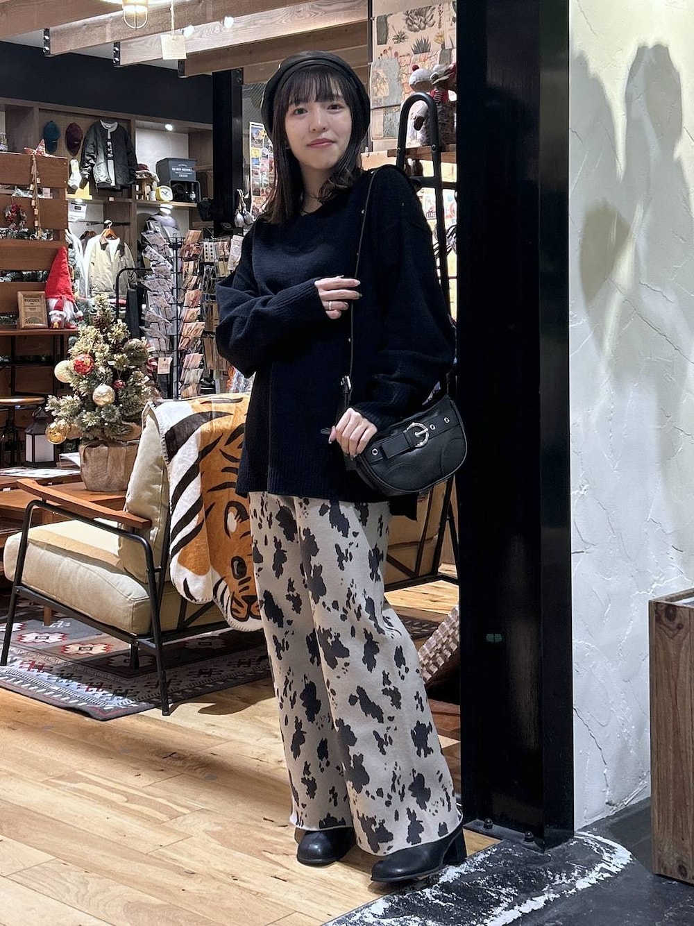 ブラック系のニット/セーター、ベージュ系のその他パンツ、ブラック系のブーツを着用したレディースの秋コーディネートの1枚目の写真