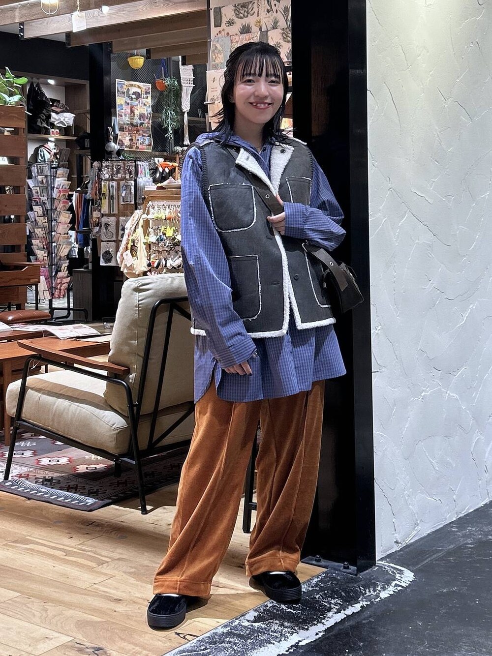 オレンジ系のその他パンツ、ブラウン系のベスト、ブラック系のスニーカーを着用したレディースの秋コーディネートの1枚目の写真