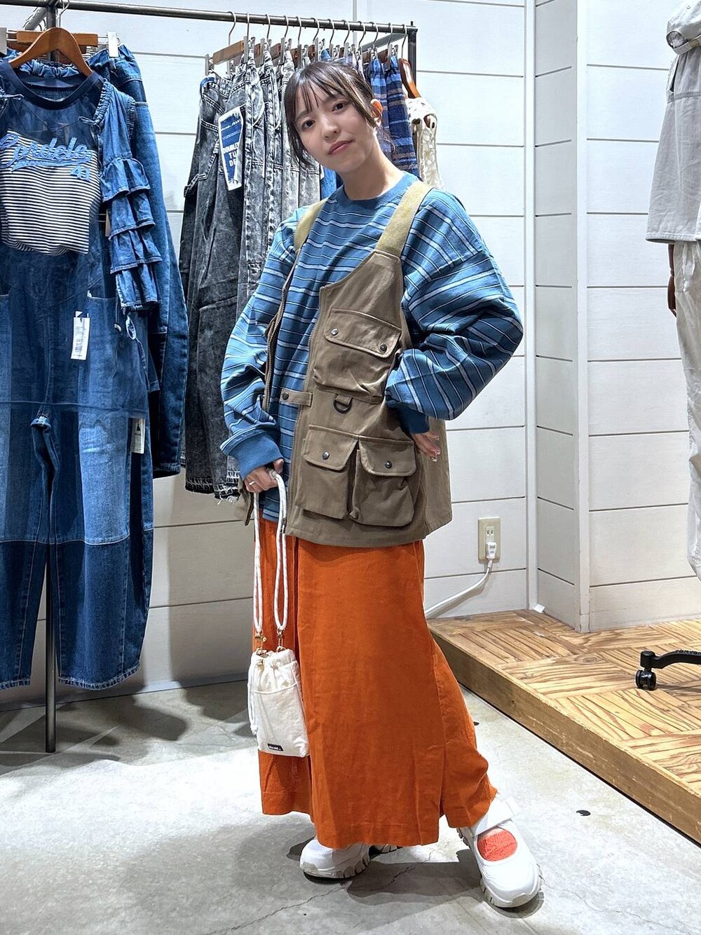 ホワイト系のショルダーバッグ、ブルー系のTシャツ/カットソー、ベージュ系のスニーカーを着用したレディースの秋コーディネートの1枚目の写真