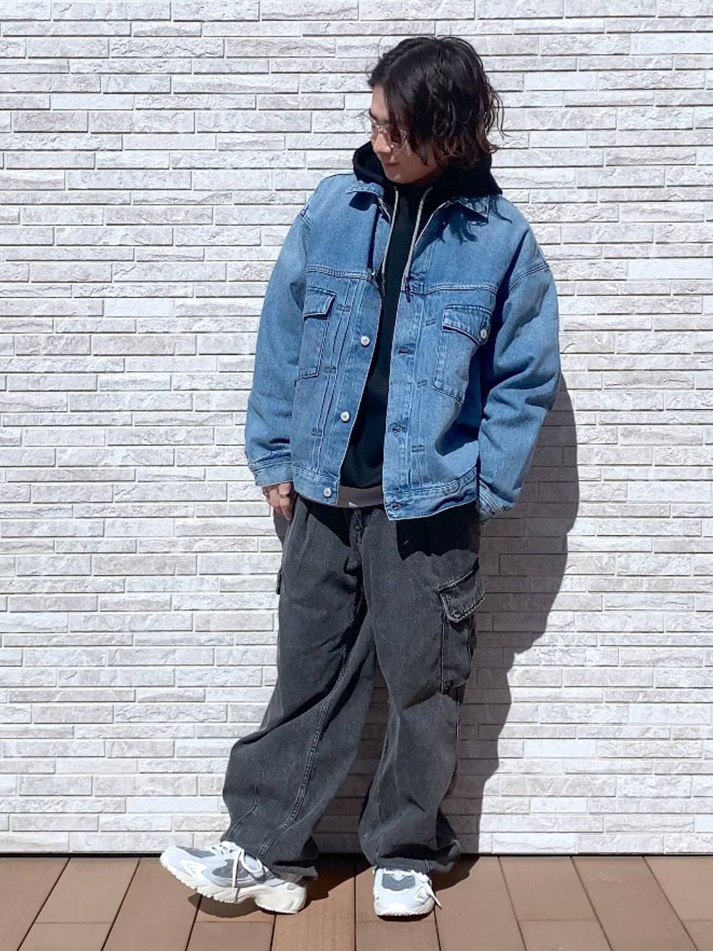 グレー系のデニムパンツ、ブルー系のデニムジャケット、ブラック系のパーカーを着用したメンズの春コーディネートの1枚目の写真