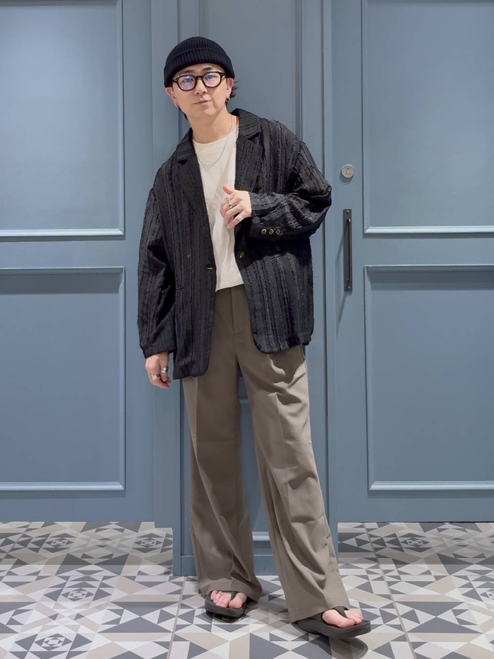 ベージュ系のスラックス、ブラック系のテーラードジャケット、ホワイト系のTシャツ/カットソーを着用したメンズの夏コーディネートの1枚目の写真