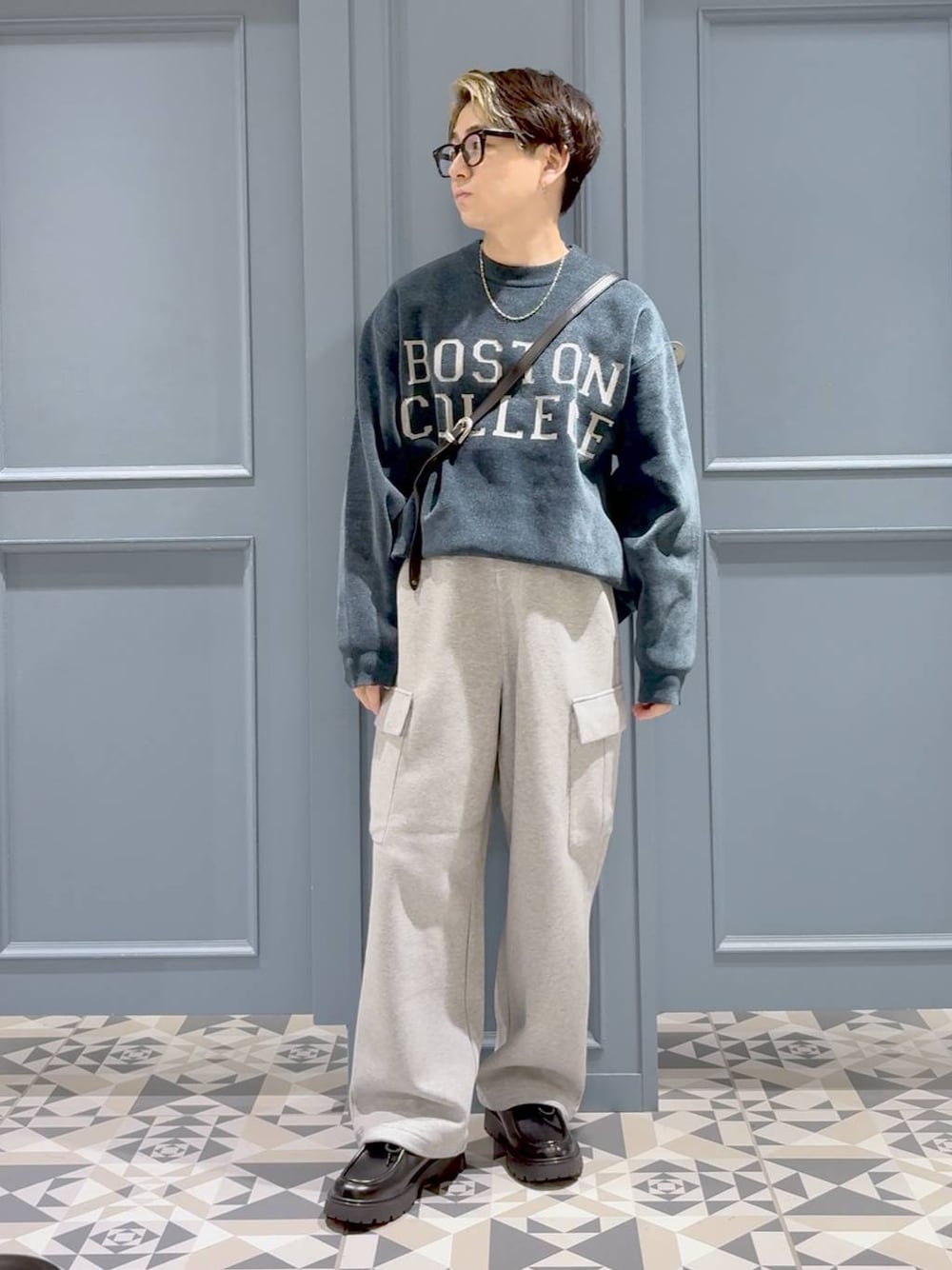 グリーン系のニット/セーター、ブラック系のドレスシューズ、グレー系のスウェットパンツを着用したメンズの秋コーディネートの1枚目の写真