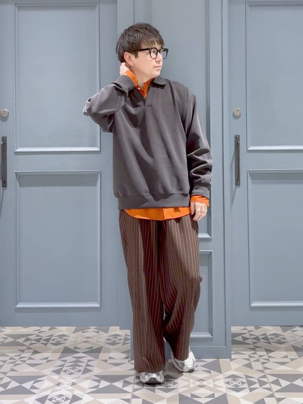 オレンジ系のシャツ/ブラウス、ブラウン系のスラックス、ブラック系のスウェットを着用したメンズの冬コーディネートの1枚目の写真