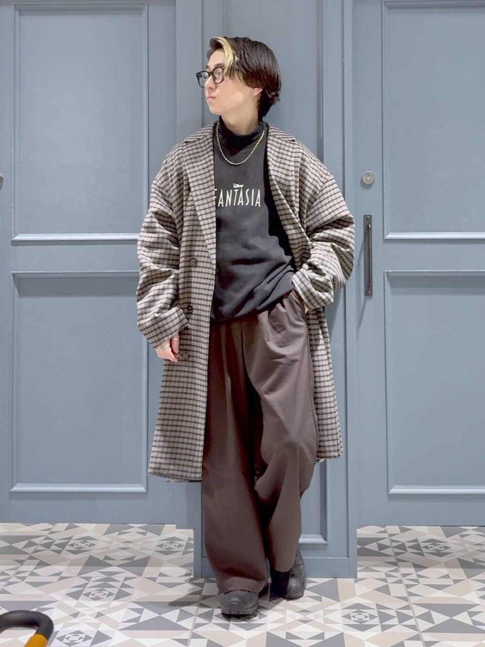 ブラック系のスニーカー、グレー系のチェスターコート、ブラック系のTシャツ/カットソーを着用したメンズの冬コーディネートの1枚目の写真