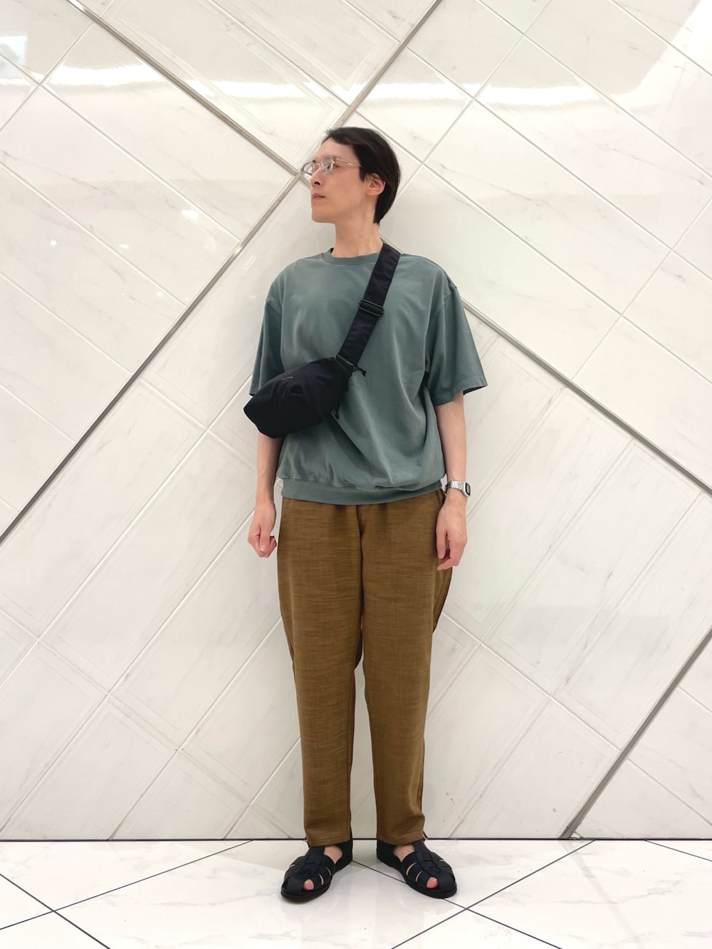 グリーン系のTシャツ/カットソー、ブラック系のショルダーバッグ、ブラウン系のその他パンツを着用したメンズの夏コーディネートの1枚目の写真