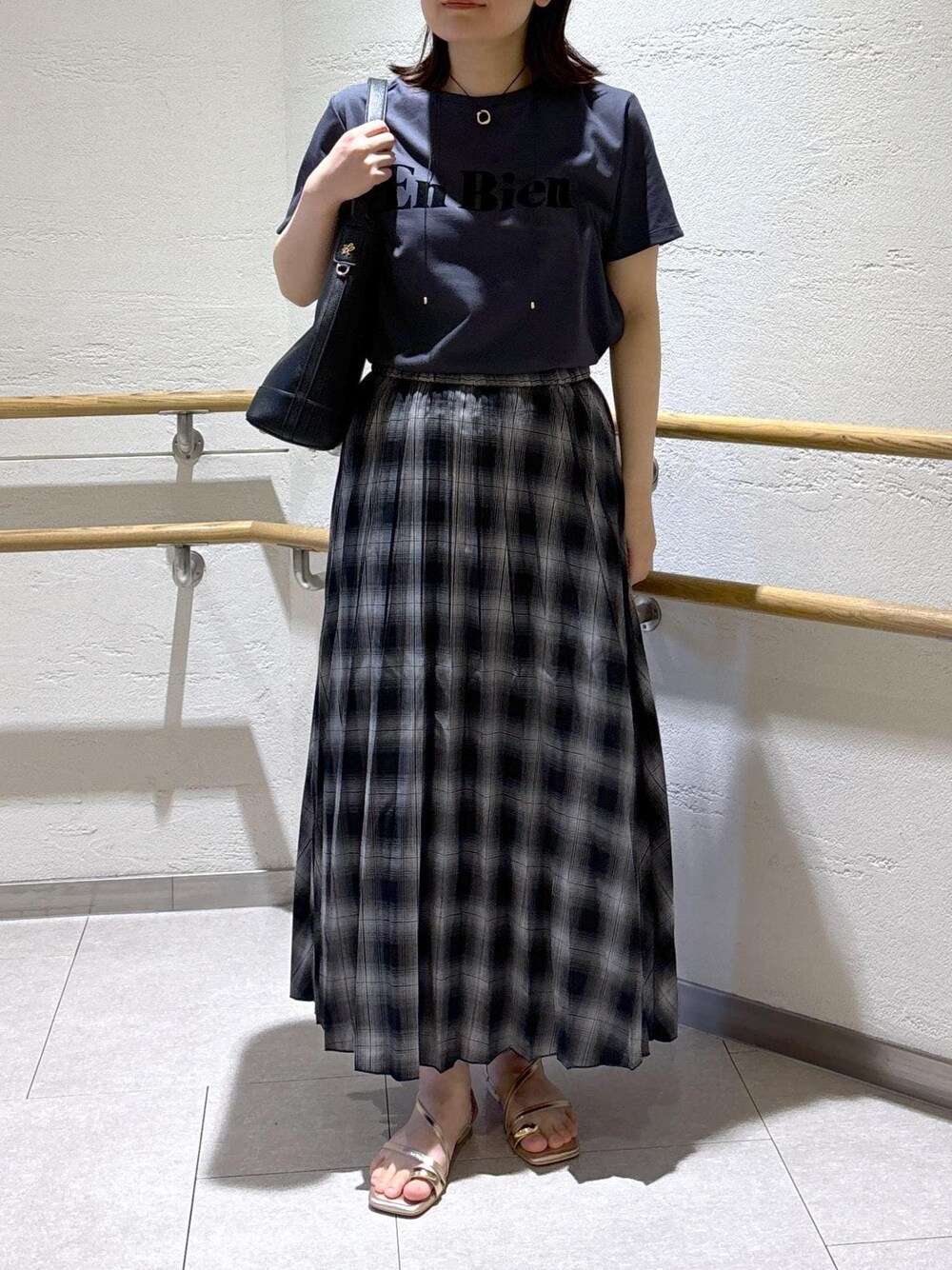 ゴールド系のサンダル、ブラック系のスカート、グレー系のTシャツ/カットソーを着用したレディースの夏コーディネートの1枚目の写真