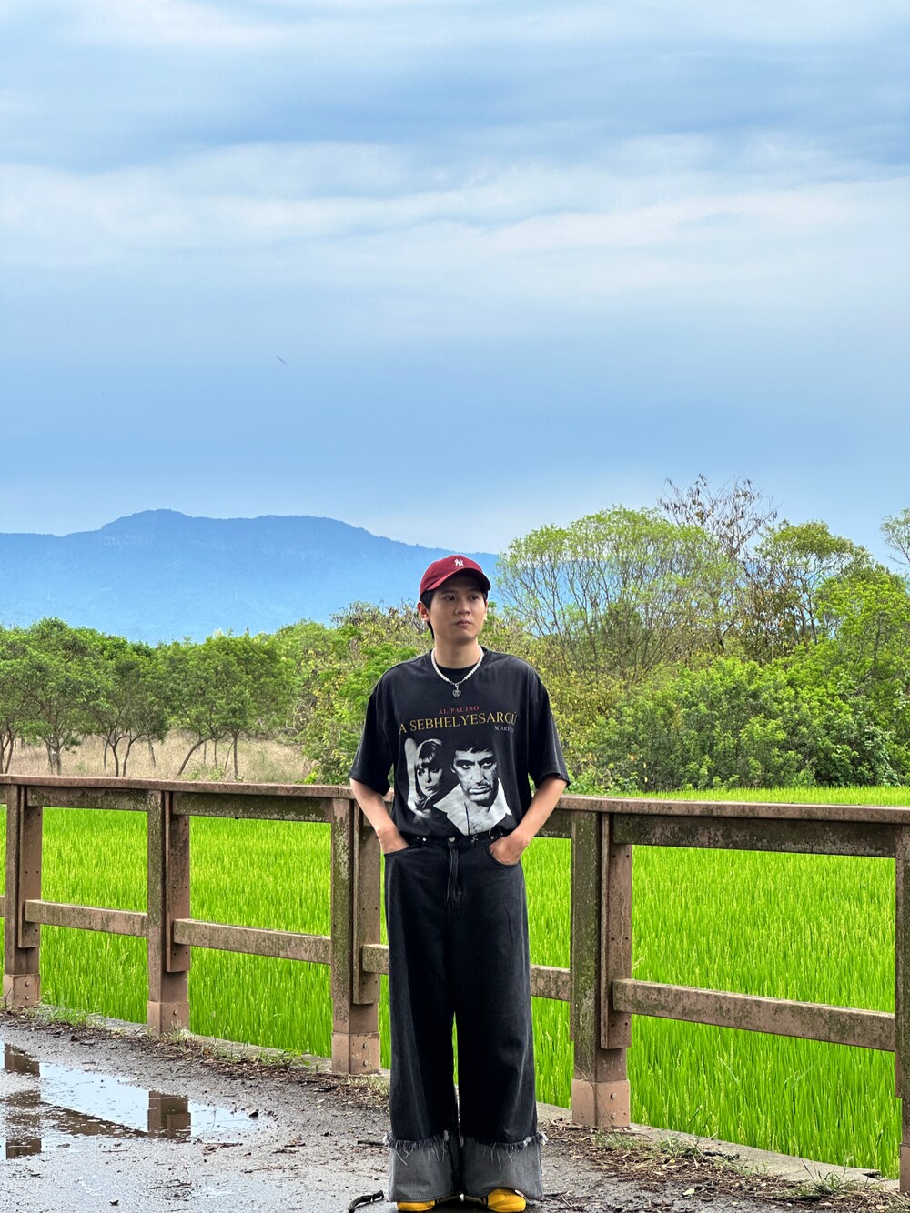 ブラック系のデニムパンツ、イエロー系のスニーカー、シルバー系のアクセサリーを着用したメンズの夏コーディネートの1枚目の写真