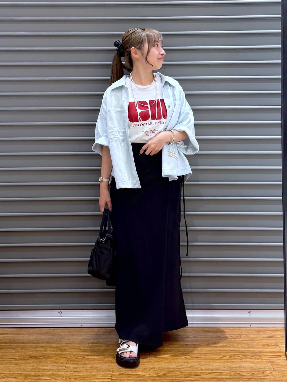 ブラック系のスカート、ホワイト系のTシャツ/カットソー、ブラック系のトートバッグを着用したレディースの夏コーディネートの1枚目の写真