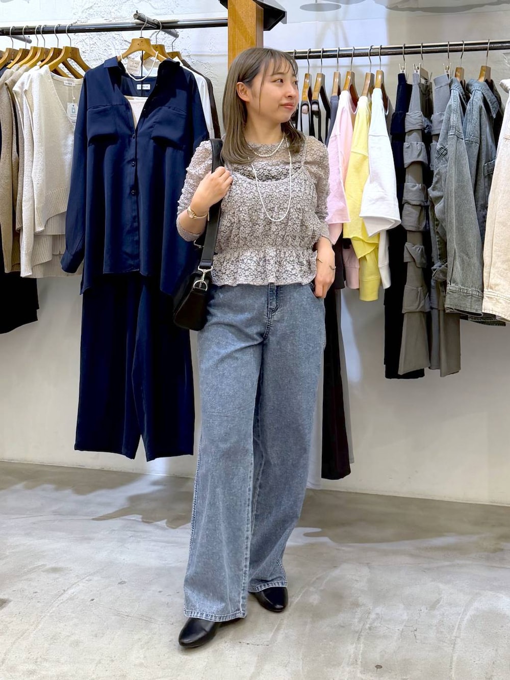ブラック系のショルダーバッグ、ブルー系のデニムパンツ、グレー系のTシャツ/カットソーを着用したレディースの春コーディネートの1枚目の写真