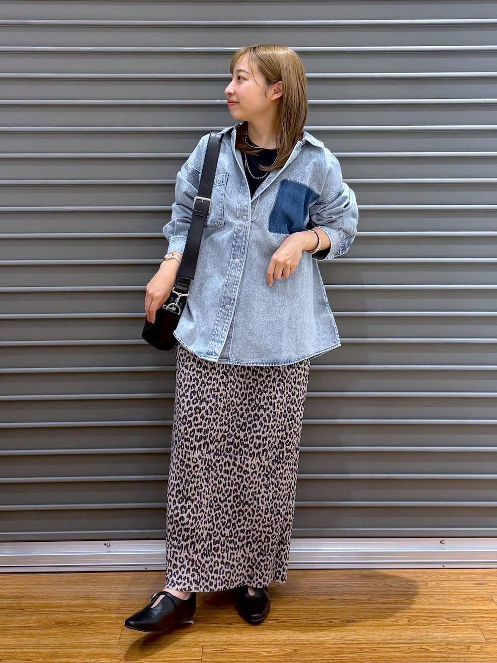 ブラック系のショルダーバッグ、ブルー系のシャツ/ブラウス、ブラック系のパンプスを着用したレディースの春コーディネートの1枚目の写真