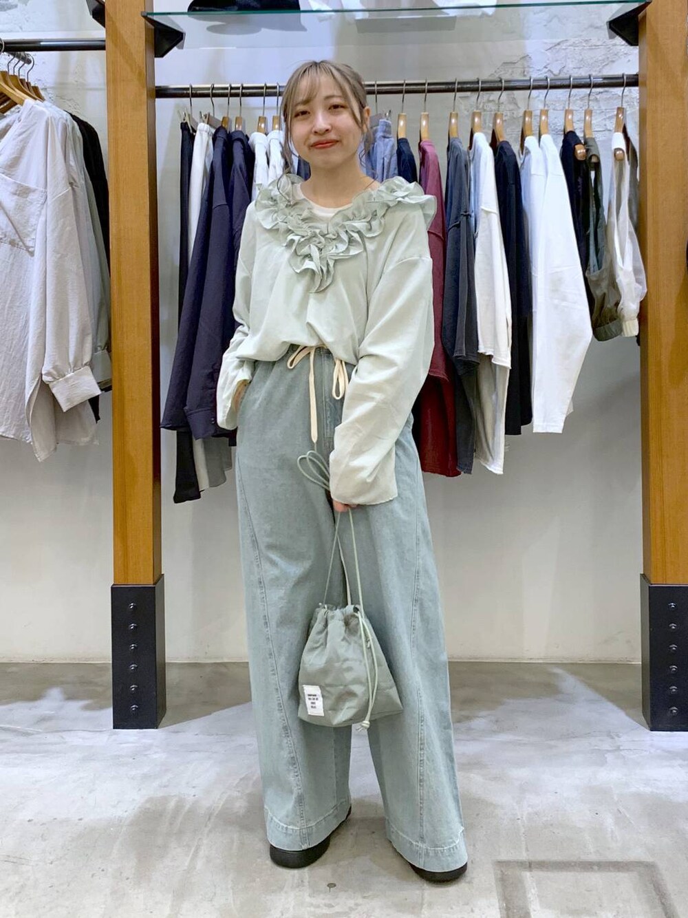 グリーン系のショルダーバッグ、ブルー系のデニムパンツ、ブラック系のサンダルを着用したレディースの春コーディネートの1枚目の写真