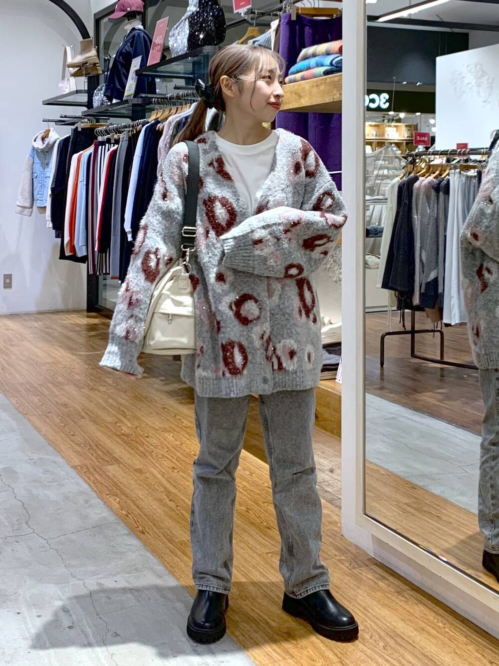 ブラック系のブーツ、グレー系のデニムパンツ、ホワイト系のショルダーバッグを着用したレディースの秋コーディネートの1枚目の写真