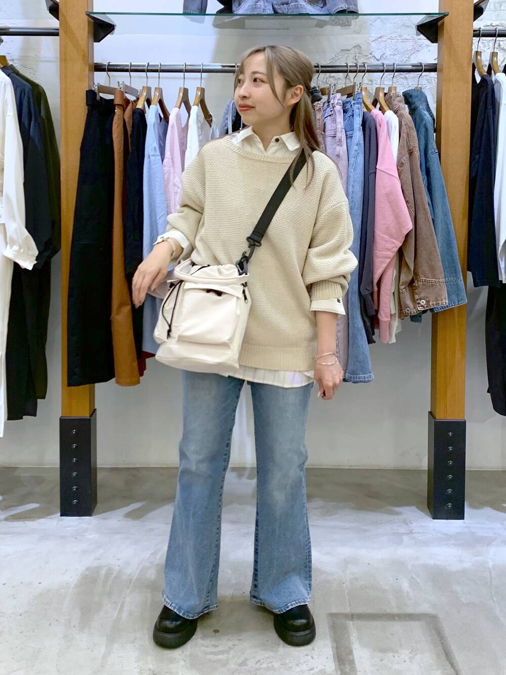 ホワイト系のショルダーバッグ、ホワイト系のニット/セーター、ブルー系のデニムパンツを着用したレディースの春コーディネートの1枚目の写真