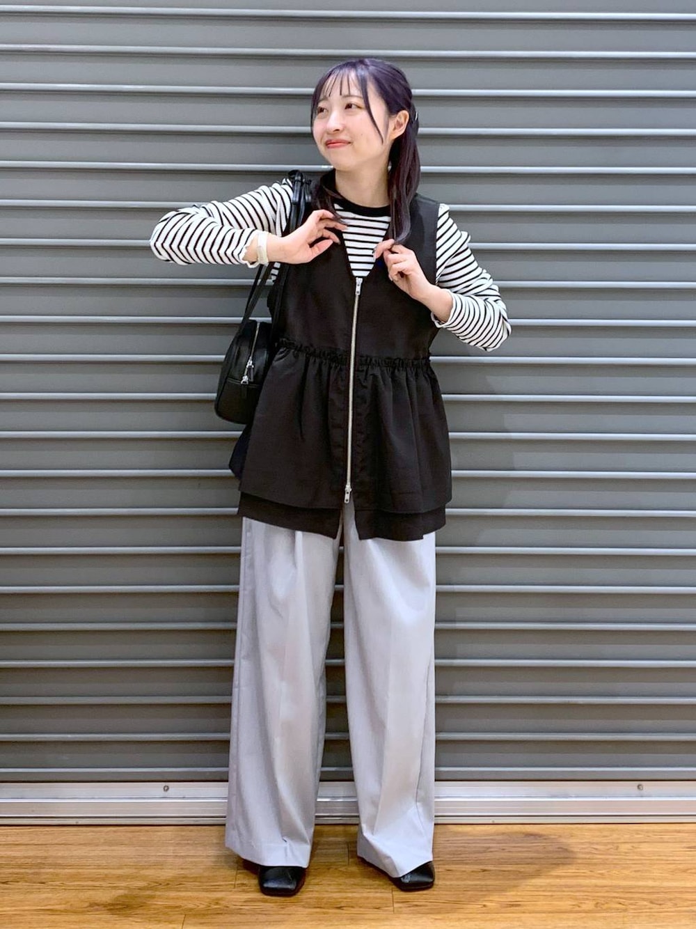 ブラック系のショルダーバッグ、ブラック系のパンプス、ブラック系のベストを着用したレディースの春コーディネートの1枚目の写真