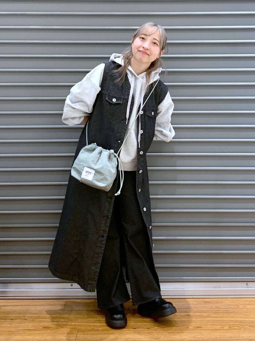 グレー系のパーカー、ブラック系のデニムパンツ、グリーン系のショルダーバッグを着用したレディースの春コーディネートの1枚目の写真