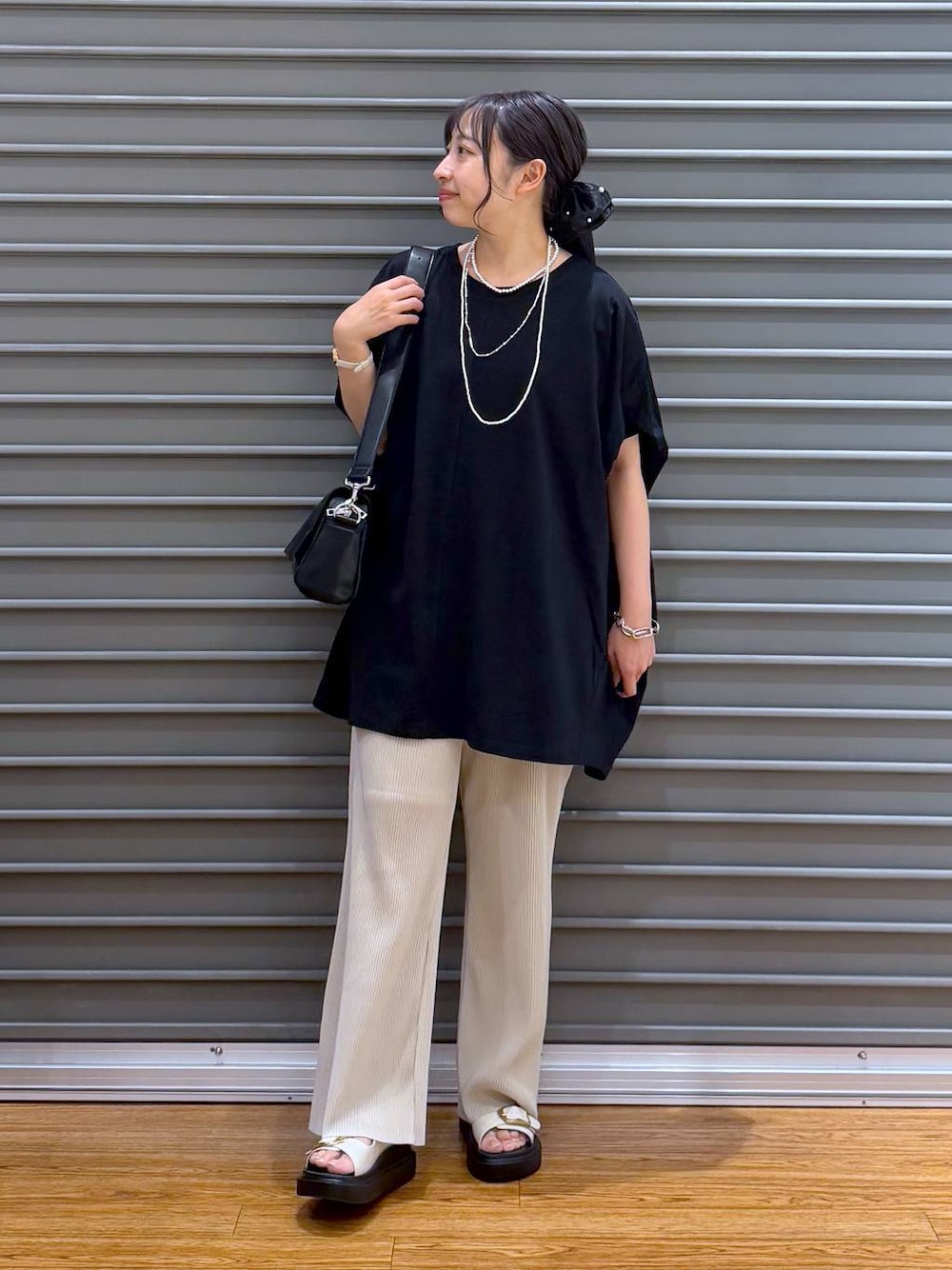 ブラック系のショルダーバッグ、ベージュ系のその他パンツ、ホワイト系のサンダルを着用したレディースの夏コーディネートの1枚目の写真