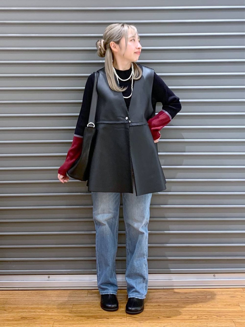 ブルー系のデニムパンツ、ブラック系のニット/セーター、ブラック系のショルダーバッグを着用したレディースの秋コーディネートの1枚目の写真